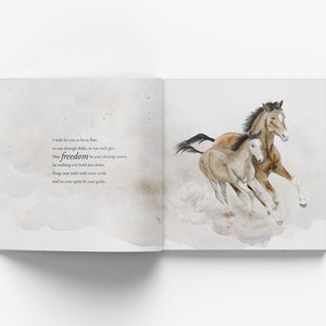 May include: A watercolor illustration of two horses running through a field. The horses are brown and white, and the background is a soft, watercolor wash of gray and white. The text "I wish for you to be so free, to run through fields, so vast with glee, may freedom be your driving crown, let nothing ever hold you down. Forge new trails with every stride and let your spirit be your guide." is written in black ink on the left page.
