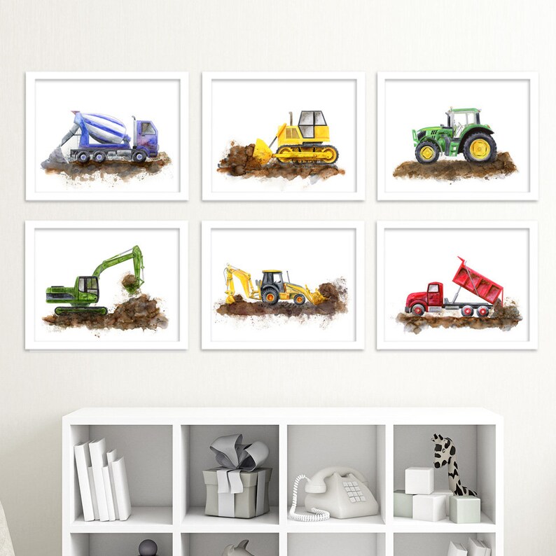 May include: Six framed watercolor prints of construction vehicles. The prints feature a blue cement mixer, yellow bulldozer, green tractor, green excavator, yellow backhoe, and red dump truck. Each vehicle is depicted on a brown dirt pile.
