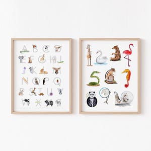 May include: Two framed wall art prints featuring watercolor animal illustrations. The left print displays an alphabet chart with animals corresponding to each letter. The right print shows a numbered chart from one to ten with various animals.