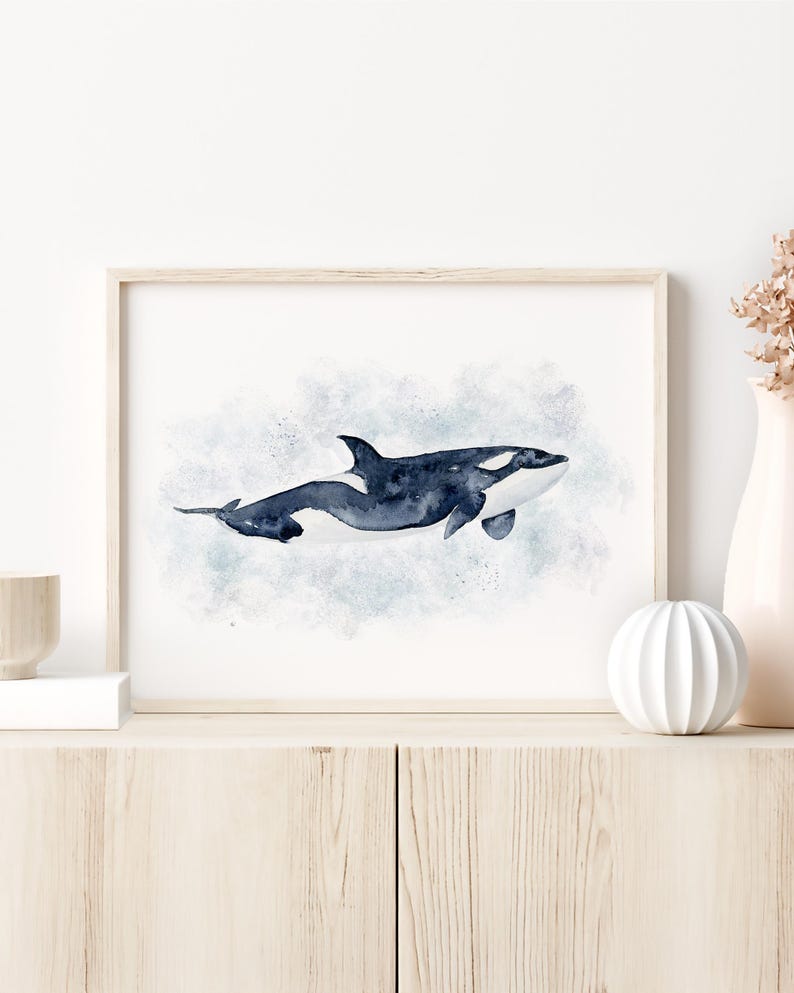 a framed watercolor painting of a whale on a white wall.