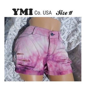 May include: Pink tie-dye denim shorts with distressed details. The shorts have a YMI Co. USA Size 11 label.