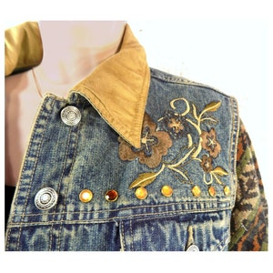 May include: A blue denim jacket with a brown corduroy collar, embroidered floral design, and gold-toned embellishments.