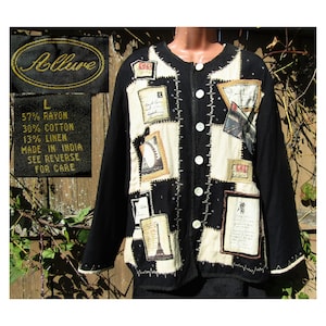 May include: Black jacket with a patchwork design featuring cream and black squares. The jacket has long sleeves and a round neckline with white buttons. Patches include images of the Eiffel Tower and other vintage designs. The label says "Allure".