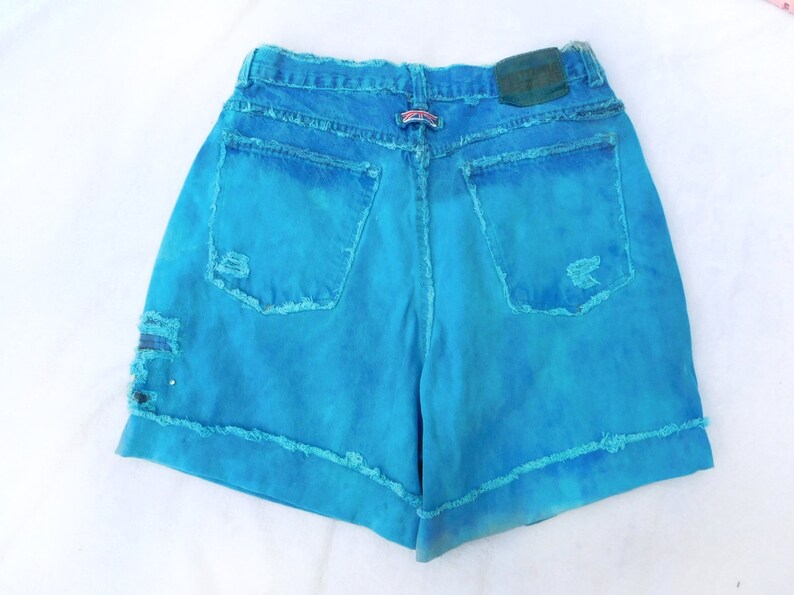 May include: Blue denim shorts with frayed edges and a distressed look. The shorts have a light blue wash and are made of a soft, comfortable fabric.