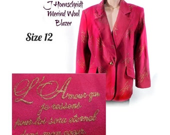 May include: A pink blazer with gold embroidery. The blazer has a single button closure and is labeled "J. Hoenscheidt Merind Wool Blazer" and "Size 12". The label also includes the text "L'Amour qui je ressent pour toi sera eternal dans mon coeur."