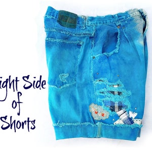 May include: A pair of blue denim shorts with distressed details and patches. The shorts have a light blue wash and are ripped and frayed around the edges. The text "Right Side of Shorts" is visible in the image.