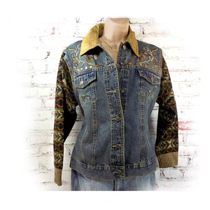 May include: A blue denim jacket with a brown suede collar and embroidered floral details on the sleeves. The sleeves are made of a brown, green, and orange patterned knit fabric.