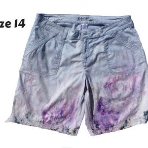 May include: Gray cargo shorts with a faded purple and pink dye pattern. The shorts have a size tag that reads "Size 14".