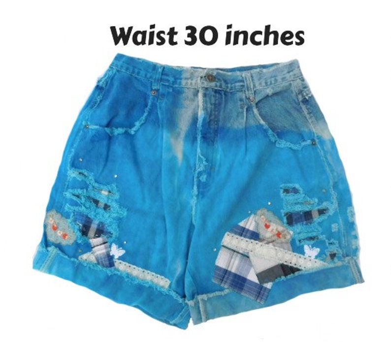 May include: Distressed denim shorts with a blue and white tie-dye pattern. The shorts have patches of fabric sewn on and are 30 inches in the waist.