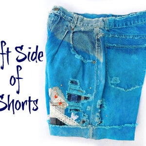May include: The left side of a pair of blue denim shorts with distressed details, patches, and a white lace trim. The shorts are a light blue color and have been heavily distressed with rips and tears.