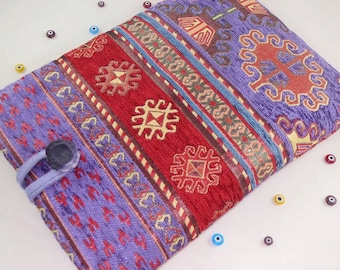 Pode incluir: Uma capa para laptop de tecido com padrão roxo e vermelho com fecho de botão. O tecido tem um design turco tradicional.