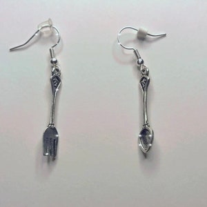 May include: A pair of silver earrings, one shaped like a fork and the other shaped like a spoon.