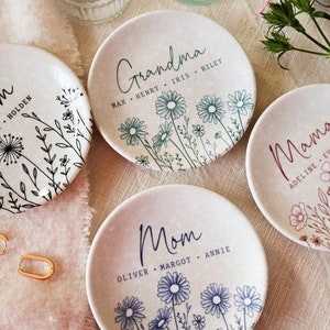 May include: Three ceramic ring dishes with floral designs and personalized text. The dishes are white with black, blue, and green floral designs. The text on the dishes reads "Grandma", "Mom", and "Mama" with the names of family members listed below.