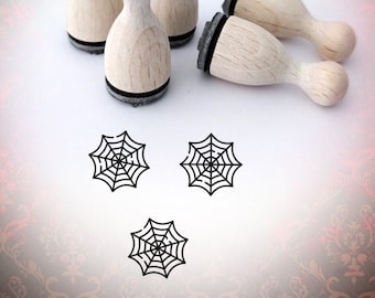 May include: Set of five wooden stamps with black ink pads, featuring a spiderweb design. The stamps are arranged on a white surface with three spiderweb impressions below.