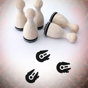 Könnte beinhalten: Holzstempel mit schwarzen Stempelkissen und einem Millennium Falcon-Design. Die Stempel sind helles Holz mit abgerundeter Oberseite und einem schwarzen Stempelkissen. Das Bild enthält auch drei schwarze Millennium Falcon-Grafiken und den Text "Bloody Nose".