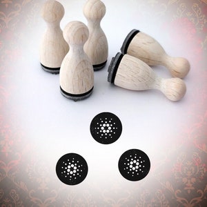 Könnte beinhalten: Fünf Stempel aus Holz mit schwarzen Stempelkissen. Die Stempel sind in Form eines abgerundeten Rechtecks mit abgerundeter Oberseite. Die Stempel sind in einem Halbkreis angeordnet, mit drei Stempeln vorne und zwei Stempeln hinten. Drei schwarze und weiße runde Stempel sind unter den Holzstempeln abgebildet.