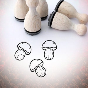 Könnte beinhalten: Vier Holzstempel mit schwarzen Stempelflächen, in Form von Pilzen, und drei Pilzillustrationen.