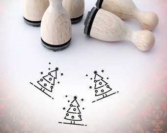 以下が含まれることがあります： クリスマスツリーのデザインが施された木製スタンプが4つ。スタンプは白い表面に配置され、そのうち3つのスタンプが表面に押印されています。スタンプには「Bloody Nose」というラベルが貼られています。