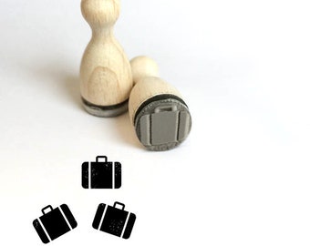 May include: Three wooden stamps with a suitcase design. The stamps are made of natural wood and have a gray rubber surface. The suitcase design is simple and modern.