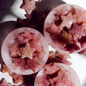 Strawberry quartz star crystals with natural pink and gold inclusions, sold as decorative healing stones to attract love, joy, and heart-centered energy.