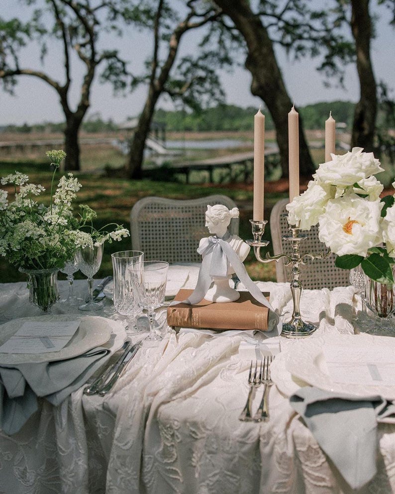 wedding reception table design with french blue silk ribbon tied around a white bust statue as a centerpiece