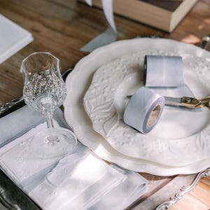 spools of hand-dyed french blue silk ribbon sitting on a plate with wedding stationery on the side with french blue silk ribbon bows