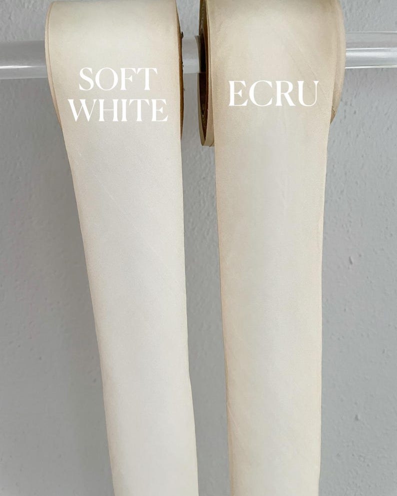 Op de afbeelding: Twee rollen lint, een met het label "SOFT WHITE" en de andere met het label "ECRU".