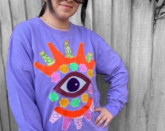 purple sweatshirt with vibrant eye appliqué, Autumn-winter clothing, statement piece, eye-catching design