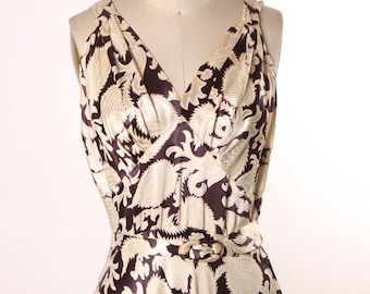 May include: A sleeveless dress with a brown and cream paisley print. The dress has a V-neckline and a belt at the waist.