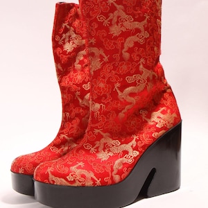 May include: Red platform boots with a gold dragon pattern. The boots have a thick platform and a chunky heel.