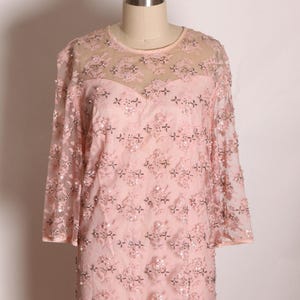 May include: A pink beaded and sequined dress with a sheer overlay and three-quarter sleeves.