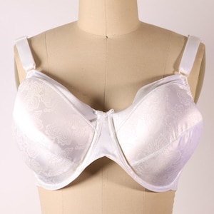 May include: A white bra with a floral pattern, displayed on a mannequin. The bra has adjustable straps and a front closure. The fabric has a subtle sheen, and the overall design is classic and elegant.