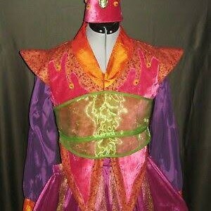 Puede incluir: Un disfraz vibrante con un corpi&ntilde;o rosa y naranja, mangas moradas y un sombrero a juego. El disfraz presenta una faja verde y dorada y adornos decorativos naranjas. El sombrero tiene un acento verde en forma de llama.