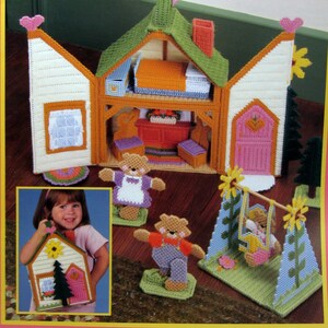 Puede incluir: Un folleto de manualidades titulado "Pack 'N' Go Bear Cottage" en lona de plástico. La portada presenta una colorida cabaña de osos tridimensional con figuras de osos y un columpio. La cabaña tiene un techo verde, una puerta rosa y paredes blancas. El folleto es de Dick Martin.