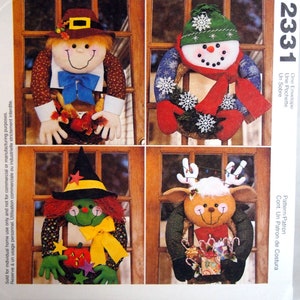 May include: McCall's Crafts pattern envelope featuring four seasonal door decorations. Includes a scarecrow, snowman, witch, and reindeer, each with unique details and festive colors. The envelope also includes the number 2331.