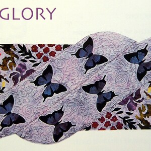 May include: A decorative textile piece with the text "SUMMER'S GLORY". The design features a light purple background with a swirling pattern, adorned with dark blue butterflies and floral elements in shades of red, orange, and purple.
