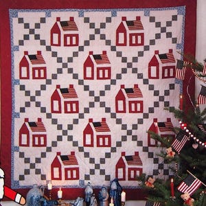 Peut inclure: Couverture du livre "Christmas Memories: A Folk Art Celebration" de Nancy J. Martin. Elle présente une courtepointe avec des maisons rouges et un sapin de Noël décoré de drapeaux. Une figurine du Père Noël est à gauche.