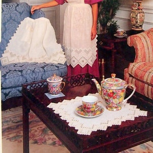 May include: A magazine cover featuring the words "Linen Lace" and "Hardanger" in cursive script. The image showcases a woman wearing an apron, with a table set with a teapot, teacup, and doilies. The background includes furniture and decorative lace.