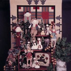 May include: A product catalog titled "Christmas Lake Lodge" featuring a collection of Christmas-themed crafts. The image showcases various handmade Santas, snowmen, and angels displayed on a shelf, with text that reads "thimbleberries, inc."