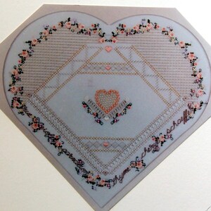 May include: A black and white cross stitch pattern for a heart-shaped design with a small heart in the center. The pattern is titled "French Roses" and is by "Cheryl Schaffer".