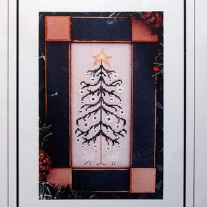 May include: A printed needlework design titled "The Button Tree" featuring a cross-stitched Christmas tree with button-like ornaments and a star on top. The design is framed within a black border and surrounded by decorative elements.