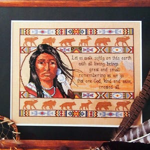 May include: A cross-stitch pattern kit titled Walk Softly by Linda K. Powell. The design features a portrait of a person with long dark hair, geometric borders, animal silhouettes, and the text: Let us walk softly on this earth with all living beings great and small remembering as we go that one God, kind and wise, created all.