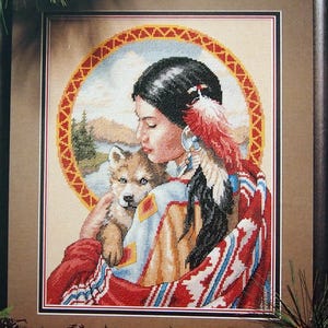 May include: A Dimensions cross stitch kit titled Guardian Spirit by James Himsworth. The packaging features a framed needlepoint design of a person with dark hair and feathers holding a wolf pup, set against a circular landscape background.