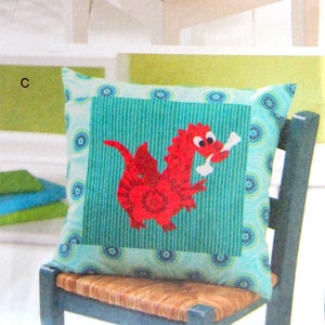 May include: Two decorative cushions, one with a pink polka dot fabric and the name "Layla" embroidered in blue, and the other with a turquoise and white striped fabric and a red dragon applique.