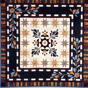 May include: A quilt pattern titled "Lilies on the Square" by Nancy Odom. The quilt design features a central square with star and floral motifs in shades of cream, brown, and blue. The border has a dark blue background with white squares and floral accents.