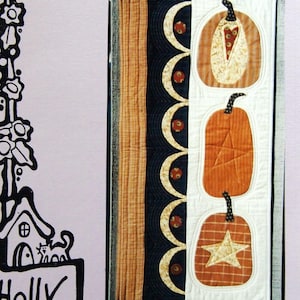 May include: A decorative banner with the text "THREE IN a ROW" features three orange pumpkin appliqués on a white background. The banner is 45.7cm x 91.4cm and includes a drawing of a hollyhock house and a pumpkin with a star.