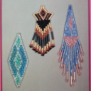 May include: A book cover titled CLASSIC EARRING DESIGNS by Nola May featuring three beaded earring illustrations. The left is a blue and green diamond shape, the center is a black, tan, and red star shape with fringe, and the right is a blue and pink triangle with long fringe.