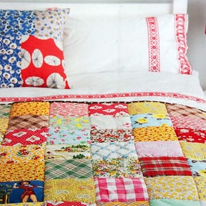 May include: A bed with a patchwork quilt and two pillows. The quilt is made of various colorful fabric squares. The pillows have a blue floral and red floral pattern. The book "a passion for Quilting" is visible.