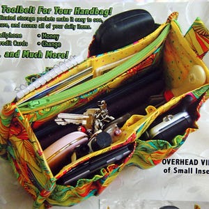May include: A patterned fabric purse insert with multiple pockets and zippers, designed to organise items like cellphones, money, and credit cards. The insert is shown open, revealing various compartments. Text on the image reads "portapockets purse insert".