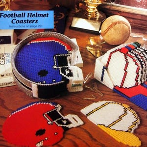 May include: A collection of handmade sports-themed items. Includes a blue and silver football helmet coaster, a red football helmet coaster, and a baseball cap coaster. Also, sport pins with various sports balls and numbers.